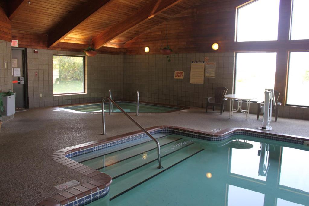 a swimming pool in a building with a table and chairs at AmericInn by Wyndham West Burlington in West Burlington