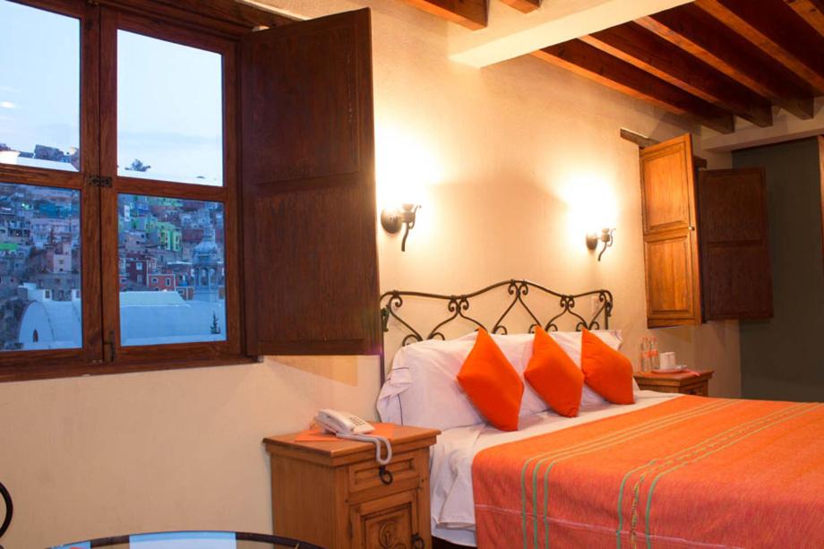 een slaapkamer met een bed met oranje kussens bij Hotel Antiguo Vapor Categoría Especial in Guanajuato