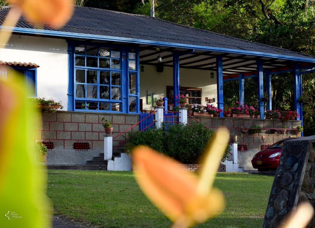 a house with blue columns and a porch with flowers at Reserva Guadalajara - Cocora Valley in Salento