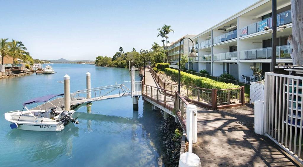 a boat docked at a marina next to a building at Jacaranda Noosa in Noosa Heads