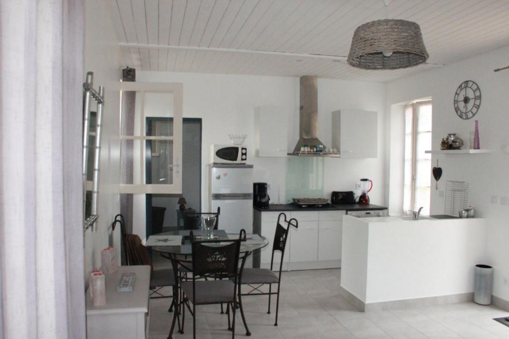 une cuisine et une salle à manger avec une table et des chaises dans l'établissement Charmante maison charentaise 