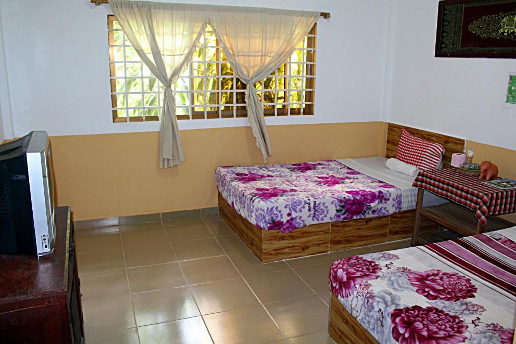1 Schlafzimmer mit 2 Betten und einem Fenster in der Unterkunft Garden Guesthouse in Kampong Chhnang