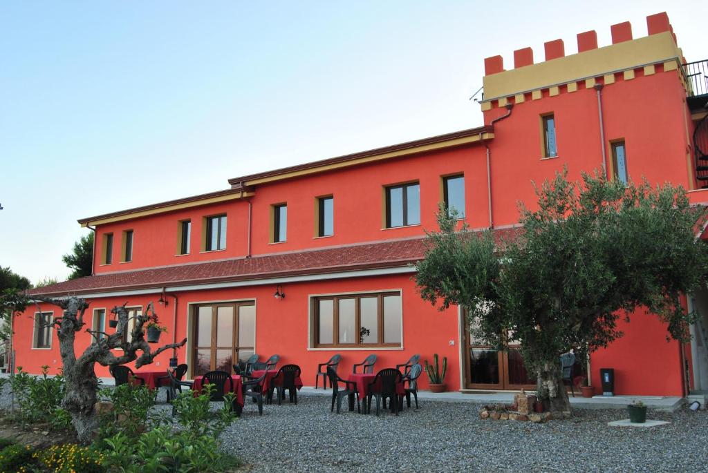 Agriturismo - B&B "La Funicolare" في Francavilla Marittima: مبنى احمر امامه طاولات وكراسي