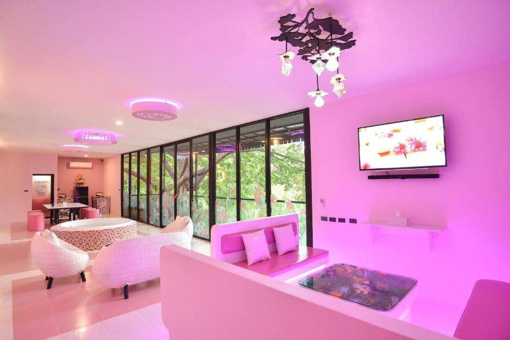 a living room with pink walls and a table and chairs at Bedvilla Chiangrai in Chiang Rai