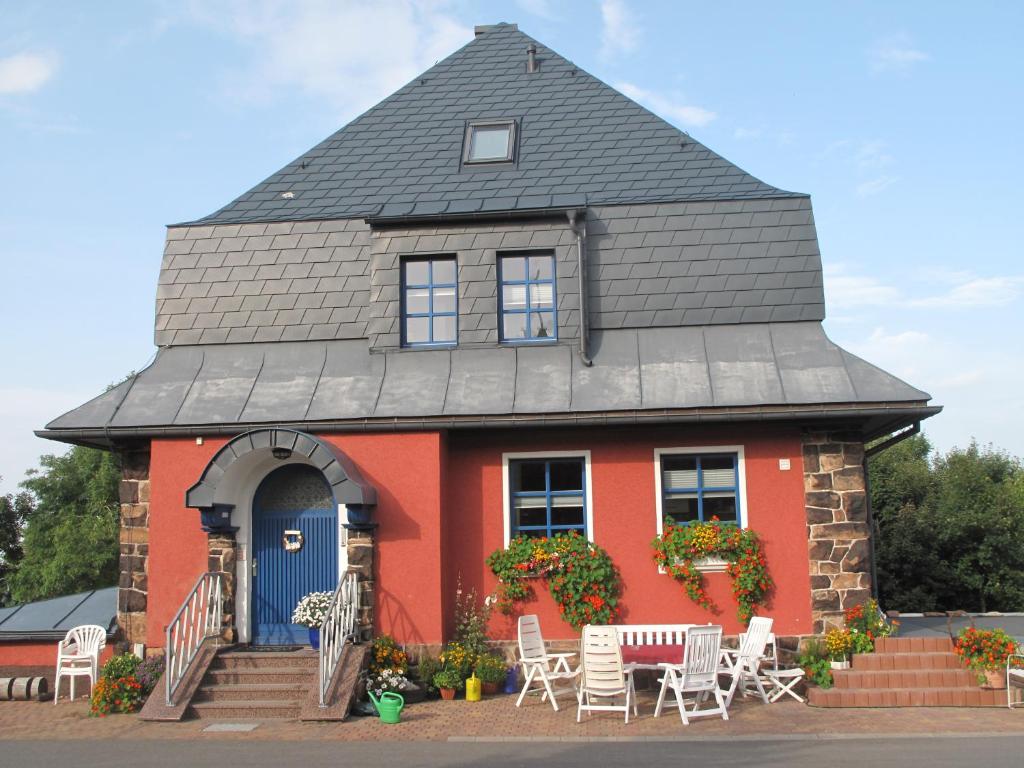 una casa roja con techo de gambrel con mesas y sillas en Beerenvilla, en Kurort Altenberg