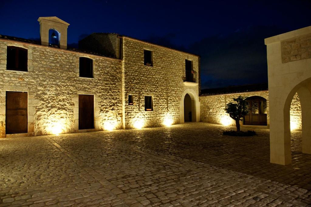 un grande edificio in pietra con luci accese di notte di Nacalino Agriturismo a Modica