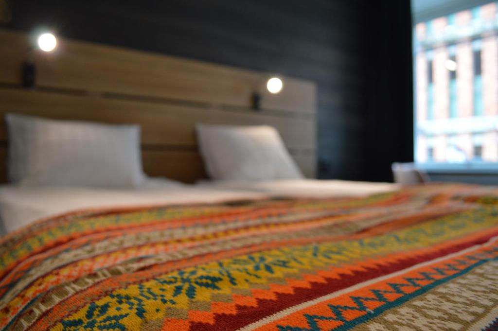 a bed with a colorful blanket on top of it at Hotell Stortorget, Östersund in Östersund