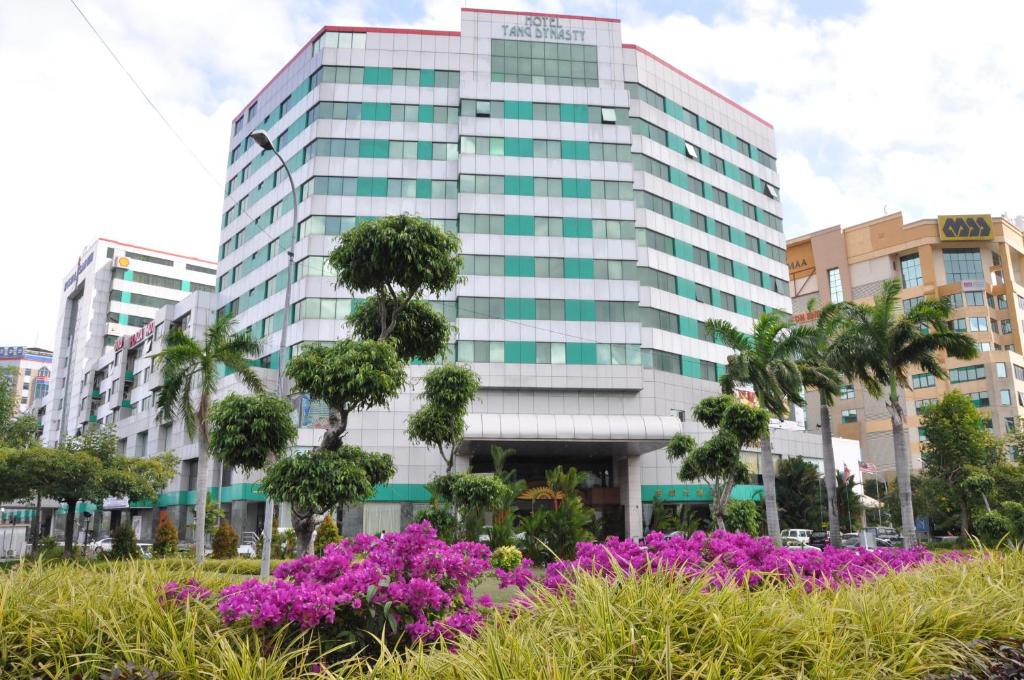 a tall building with purple flowers in front of it at Tang Dynasty Hotel in Kota Kinabalu