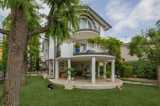 ein großes weißes Haus mit einem Baum im Hof in der Unterkunft Villetta Il Glicine in Porto Mantovano
