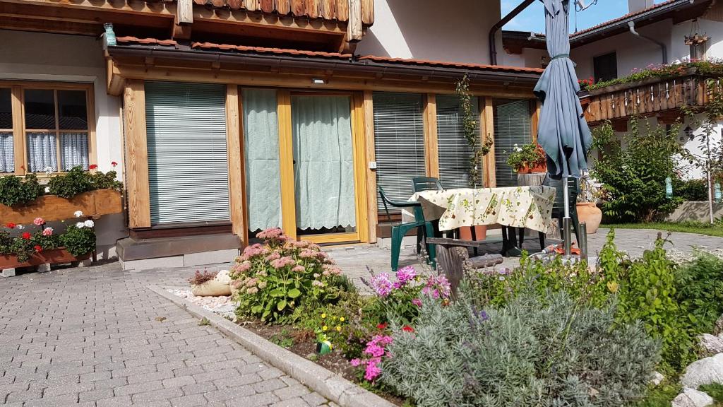 eine Terrasse mit einem Tisch, einem Sonnenschirm und Blumen in der Unterkunft Bina' s house in Sillian