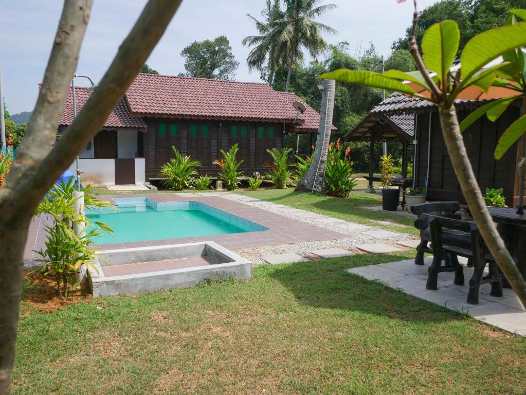 a swimming pool in a yard next to a house at Kampung Tok Lembut Vacation Home in Pantai Cenang