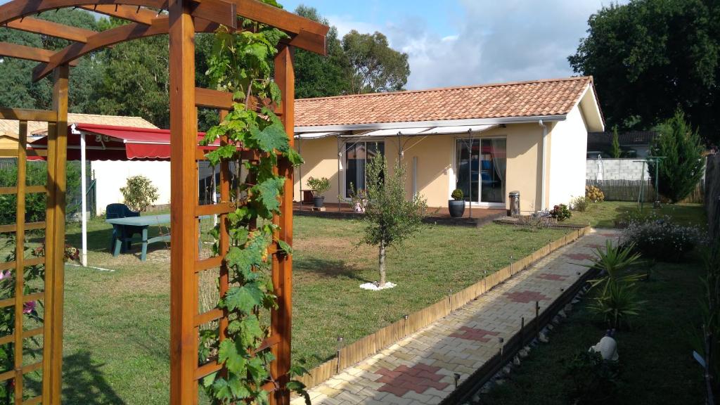 uma casa com um jardim com uma pérgola em La Cazaline em Cazaux