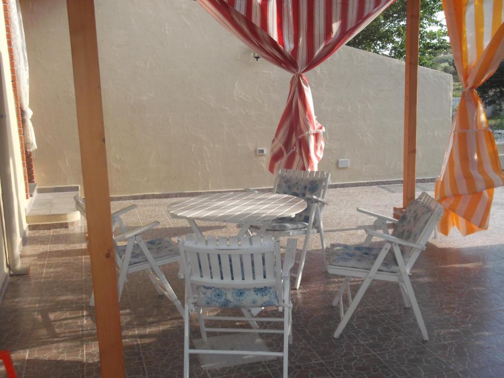 un tavolo e sedie su un portico con ombrellone di Diletta a Cala Liberotto