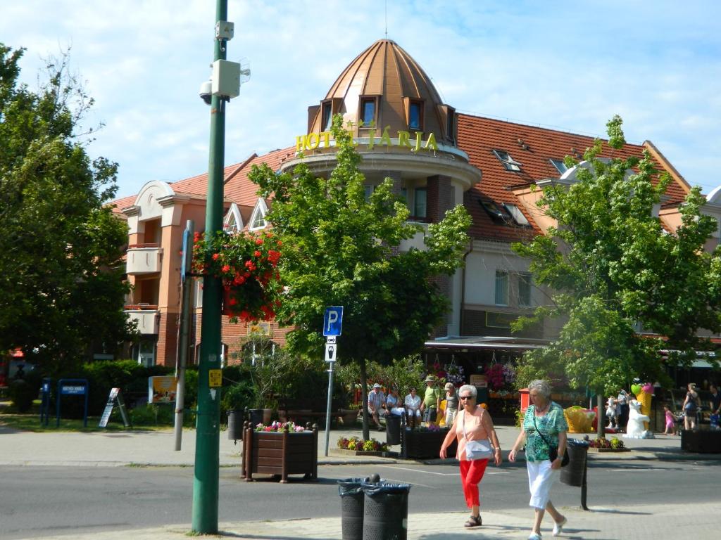 two women walking down a street in front of a building at Héli apartman in Hajdúszoboszló