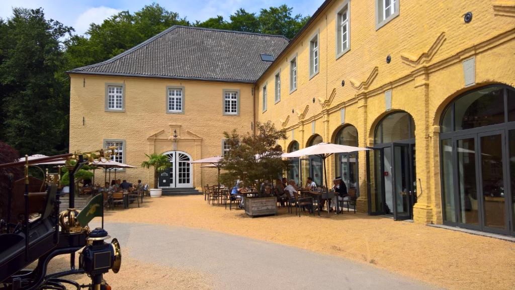 un edificio con gente sentada en mesas delante de él en Hotel Schloss Dyck, en Jüchen