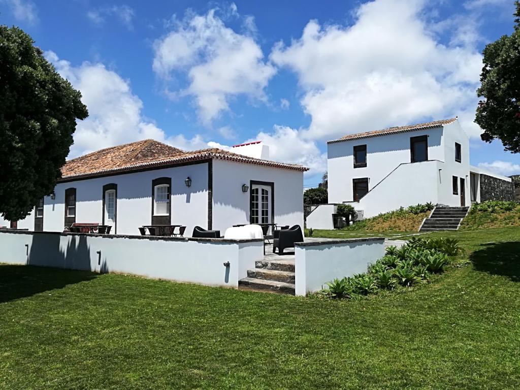 ein weißes Haus mit grünem Rasen davor in der Unterkunft Quinta Nossa Senhora do Cabo in Lagoa