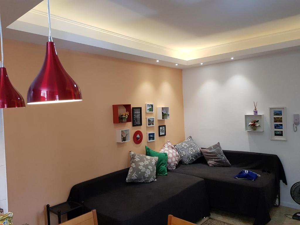 a living room with a black couch and red pendant lights at Temporada Rio Studio Lily 1 - Perto do Cristo e Copacabana in Rio de Janeiro