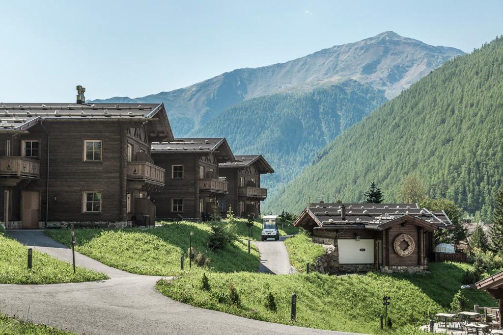 a group of wooden buildings in a valley with mountains at Hotel & Chalets Edelweiss in Madonna