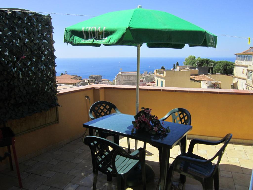 a blue table with a green umbrella on a balcony at Taormina Terrace sea view in Taormina