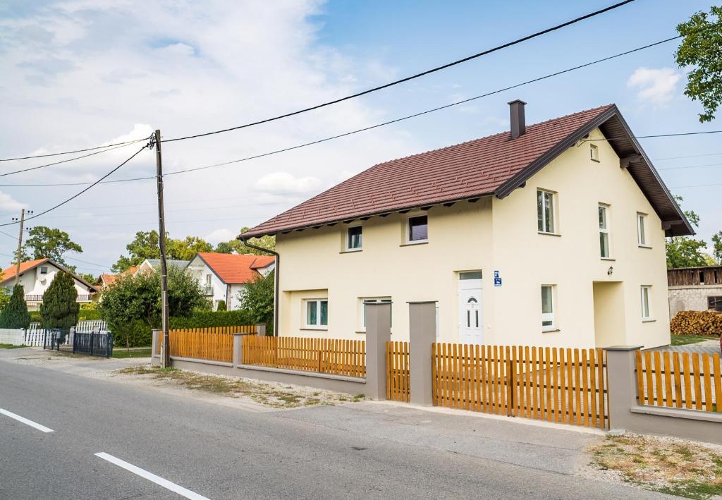 Biały dom z drewnianym płotem w obiekcie Tina Rooms w mieście Velika Gorica