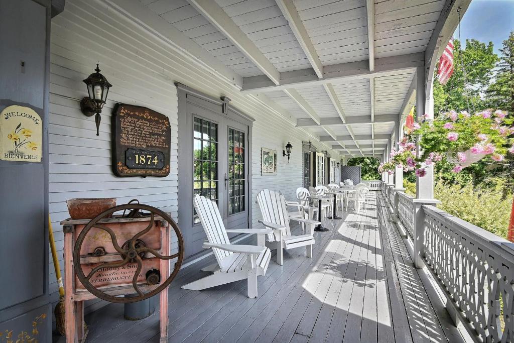 - une terrasse couverte avec des chaises blanches et un panneau sur celle-ci dans l'établissement Auberge Lakeview Inn, à Lac-Brome