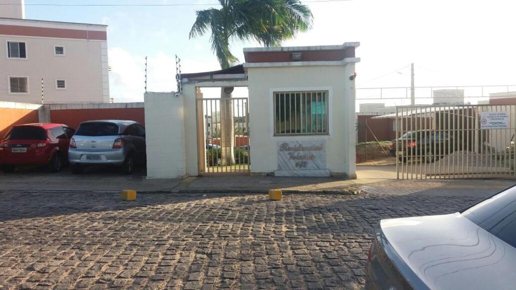 un edificio con una puerta y coches aparcados en un aparcamiento en Apartamento em Natal/RN, en Natal