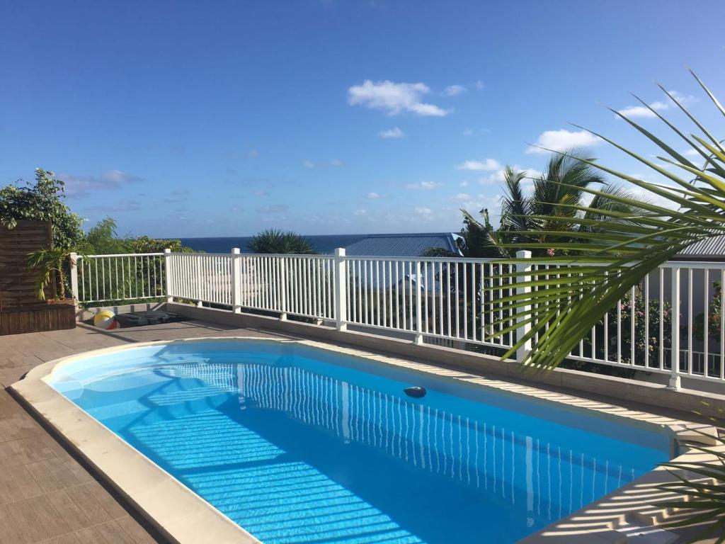 a swimming pool on a balcony with the ocean in the background at Mango Sea -Villa "Maracudja" et appartement "Jojoba" avec piscine & vue sur les îles in Saint-François