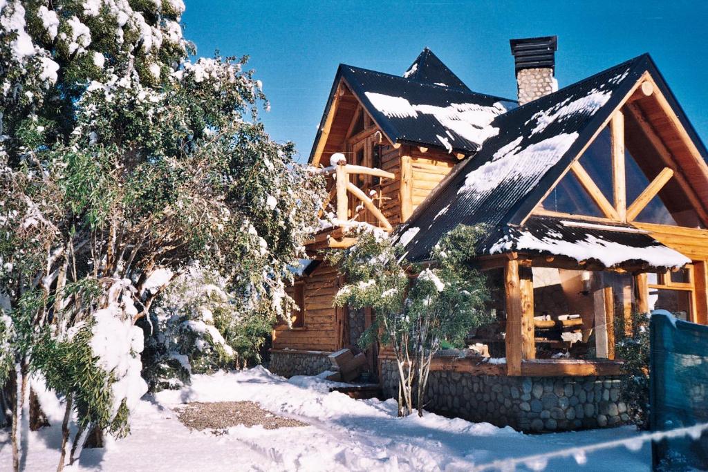 Cabaña de madera con nieve en el techo en Cabañas Lemu Hue en San Carlos de Bariloche