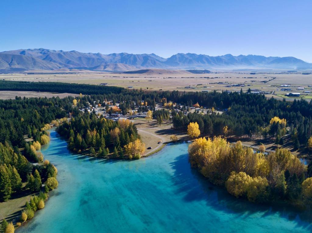 an aerial view of a river with trees and a town at Lake Ruataniwha Holiday Park in Twizel