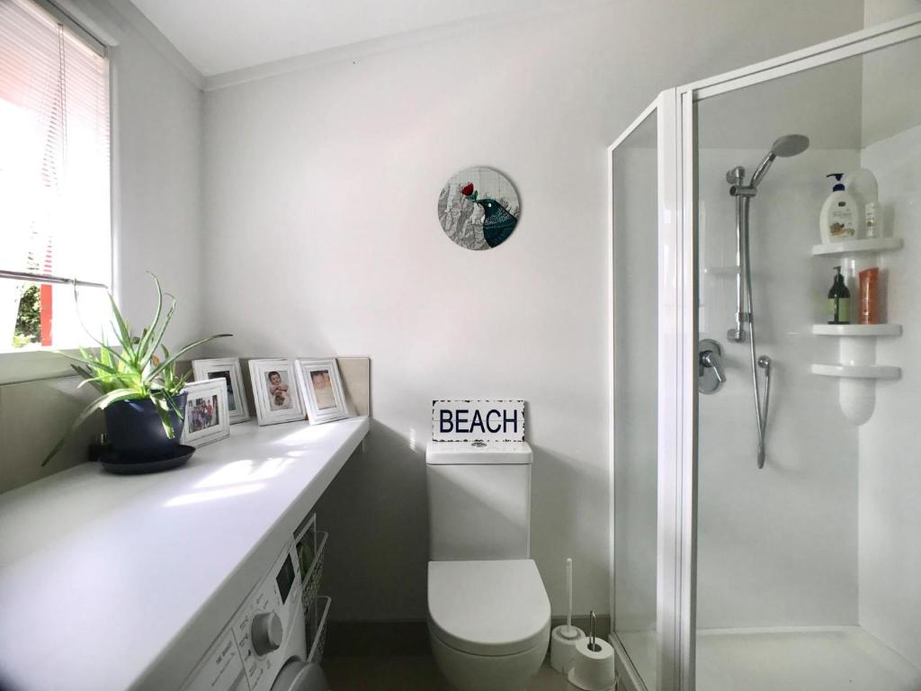 a white bathroom with a toilet and a shower at The But n Ben in Christchurch