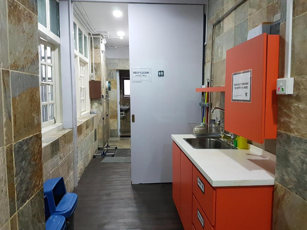 een keuken met oranje kasten en een wastafel bij Royal Lodge @ Pagoda Street in Singapore