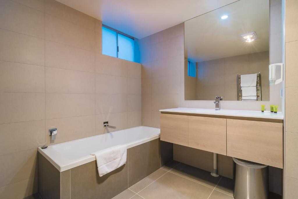 a bathroom with a tub and a sink and a mirror at Argosy Motor Inn in Devonport