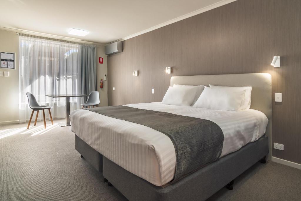 um quarto de hotel com uma cama grande e uma mesa em Argosy Motor Inn em Devonport