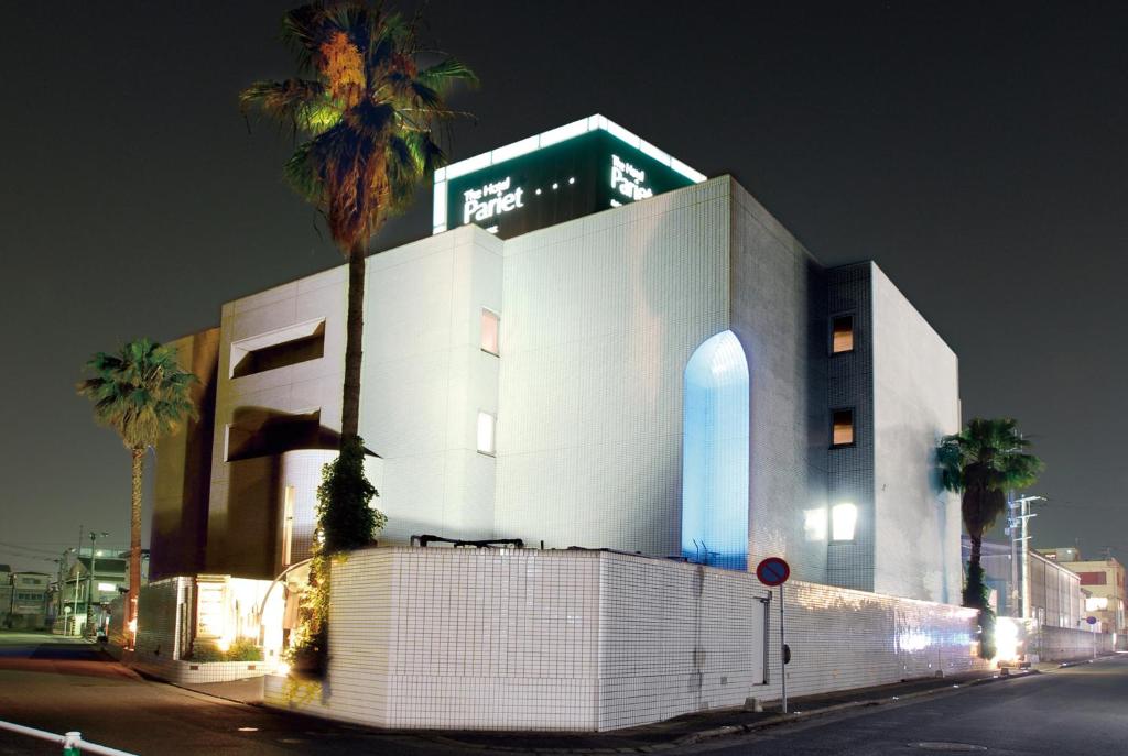 ein weißes Gebäude mit einer Palme davor in der Unterkunft Hotel Pariet (Love Hotel) in Fukuoka