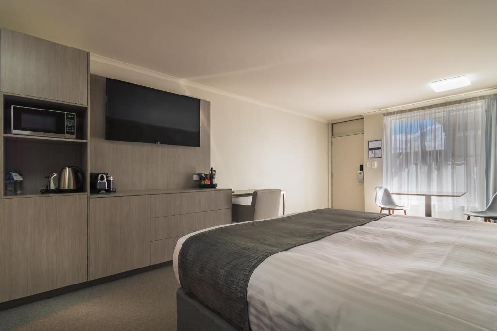 a bedroom with a large bed and a flat screen tv at Argosy Motor Inn in Devonport