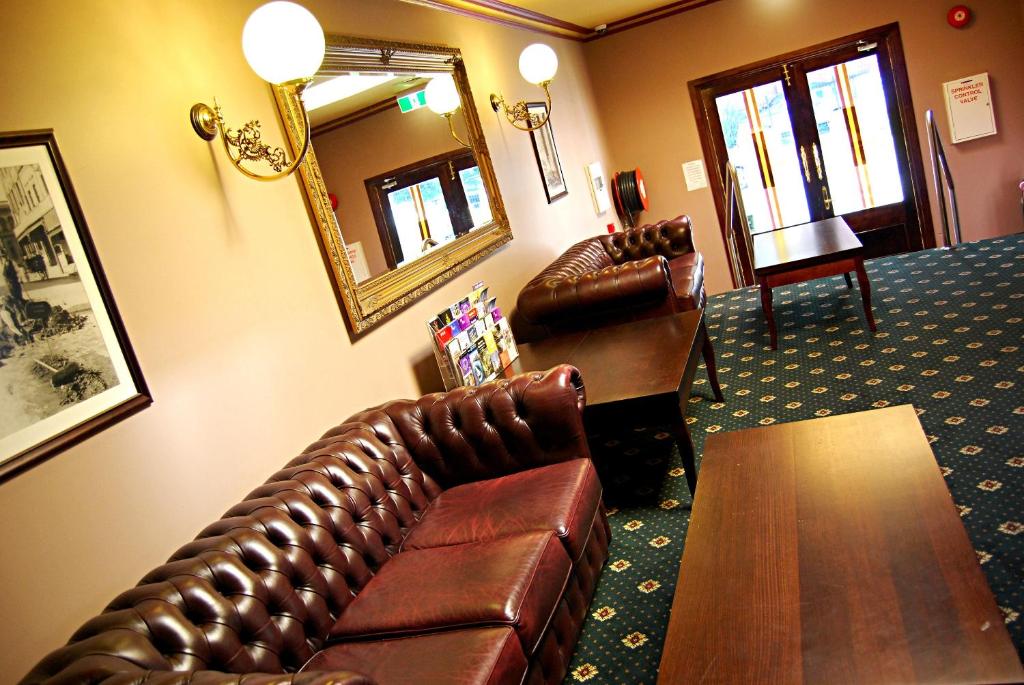 a living room with a leather couch and a table at The Glenferrie Hotel Hawthorn in Melbourne