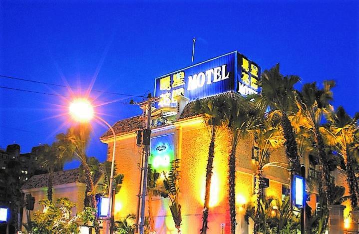 a building with a neon sign on top of it at Lestar Motel in Taoyuan