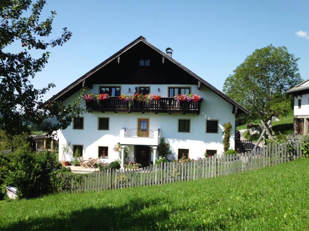 a white house with flowers on a balcony at Leitingerhof in Thalgau