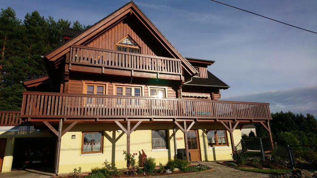 a large wooden house with a balcony on top at Ferienwohnng Sander in Halsbrücke