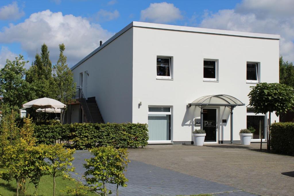 een wit gebouw met een oprit naar binnen bij Pur Hotel in Emlichheim