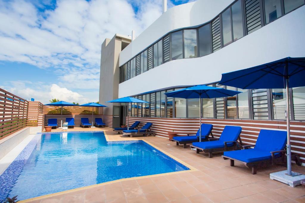 a pool with blue chairs and umbrellas next to a building at Residence Potosi in Trou aux Biches