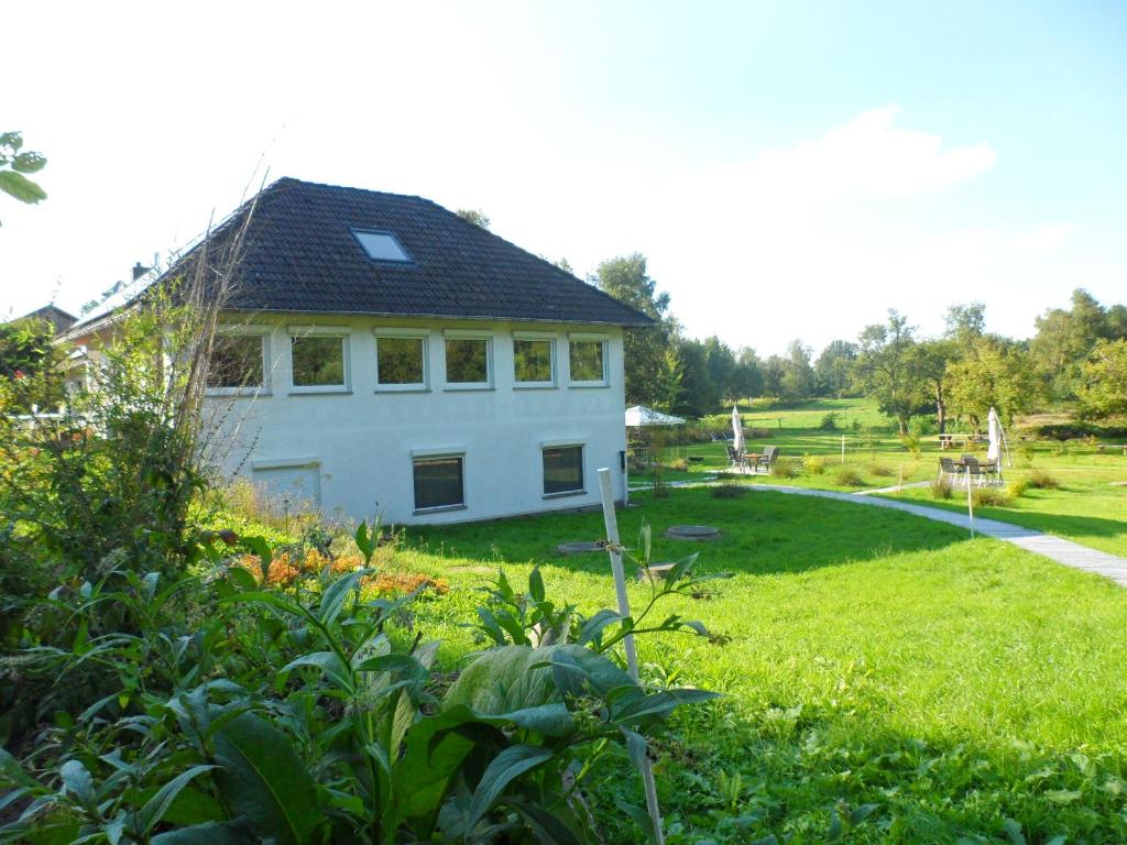 Ein weißes Haus auf einem Feld mit einem Hof in der Unterkunft Buntes Moor in Grasberg