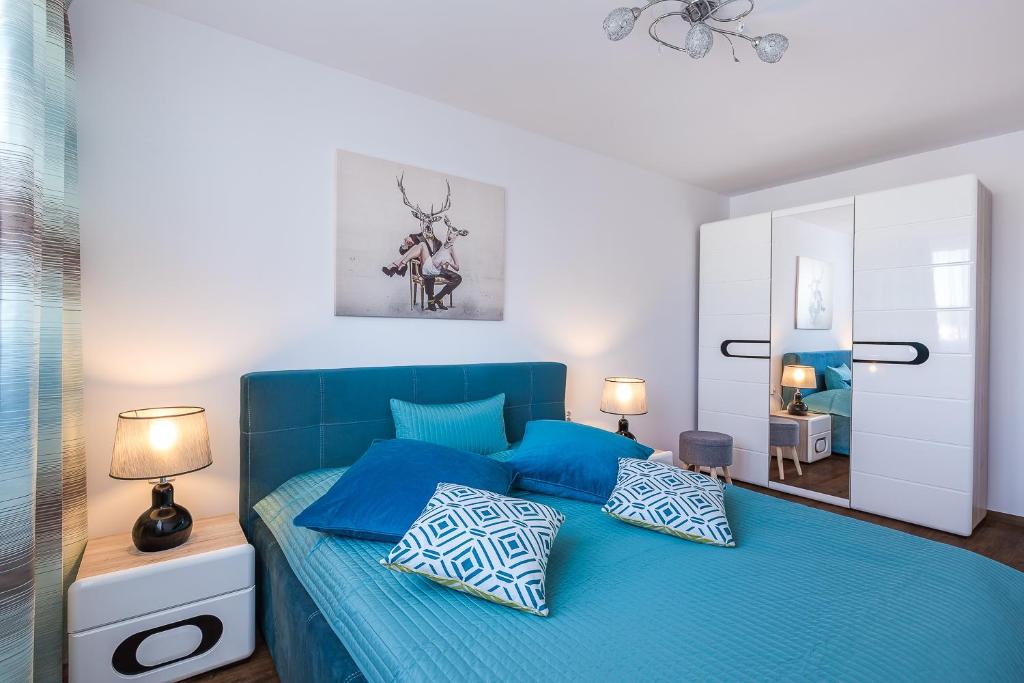 ein blaues Bett mit blauen Kissen im Schlafzimmer in der Unterkunft Apartament Stag Azyl na szczycie - 2 osobne pokoje - by Space Apart in Jelenia Góra