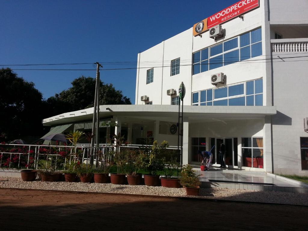 un edificio blanco con macetas delante de él en Woodpecker Resort Hotel, en Banjul