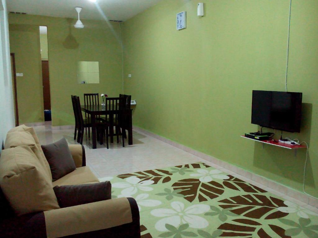 a living room with a couch and a flat screen tv at Jati Indah Homestay in Malacca