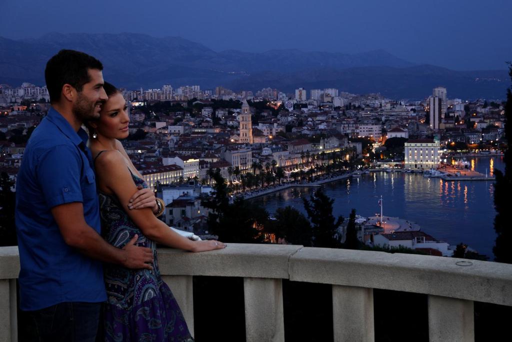 a man and a woman standing on a balcony overlooking a city at S Luxury Apartments in Split