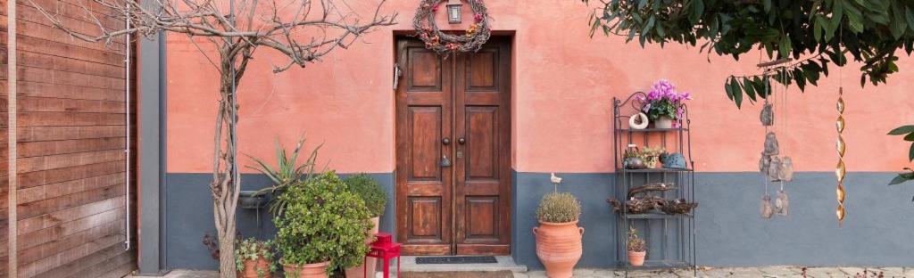 a pink building with a wooden door and some plants at La casetta di Lu in Cellarengo