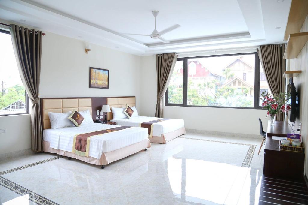 a bedroom with two beds and a large window at Iris Hotel in Ha Long