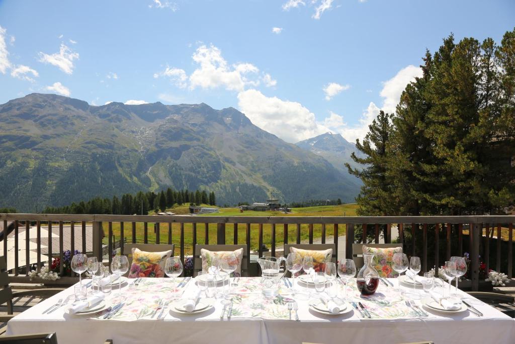 una mesa con copas de vino en un balcón con montañas en Luxus Apartments Chesa Chantarella an TOP Lage! en St. Moritz