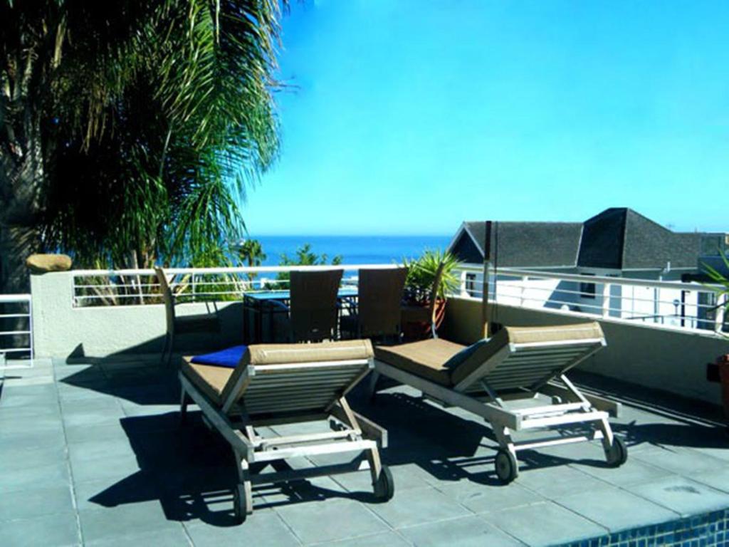 2 sedie e un tavolo su un patio con vista sull'oceano di Maison Fontainbleau a Città del Capo